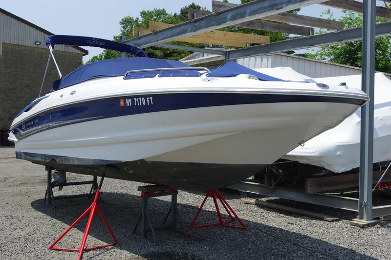 Slide: The Image of 2004 Crownline 240 EX boat on stands, blue cover, outdoor storage. - 1