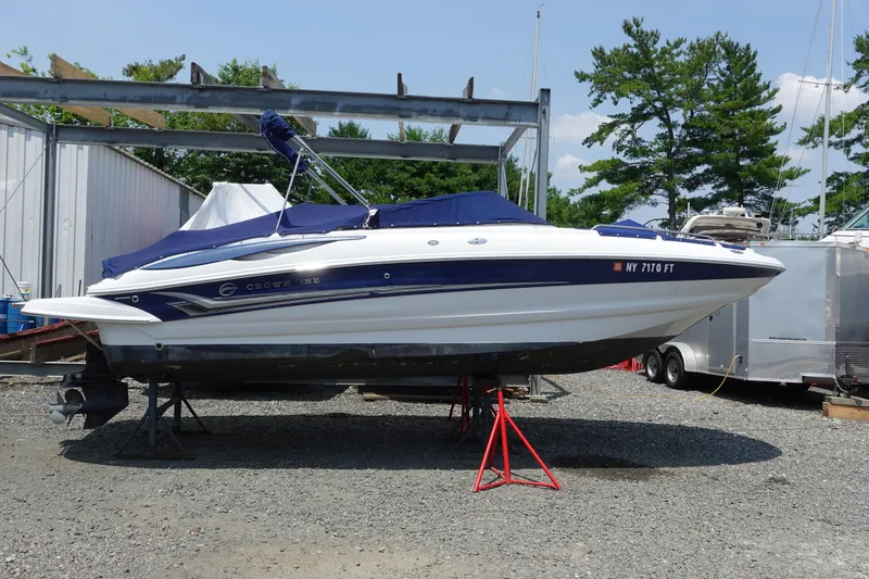 The Image of 2004 Crownline 240 EX boat on stands, covered, in outdoor storage area. - 0