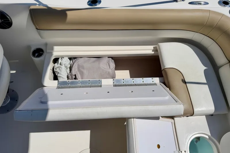 Slide: The Image of 2016 Key West 203 DFS boat seat storage compartment with open lid and stored items. - 28