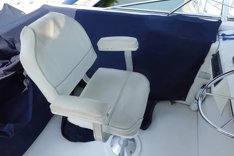 Slide: The Image of Captain's chair on 2000 Bayliner 4788 Pilot House Motoryacht, featuring white upholstery and armrests. - 11