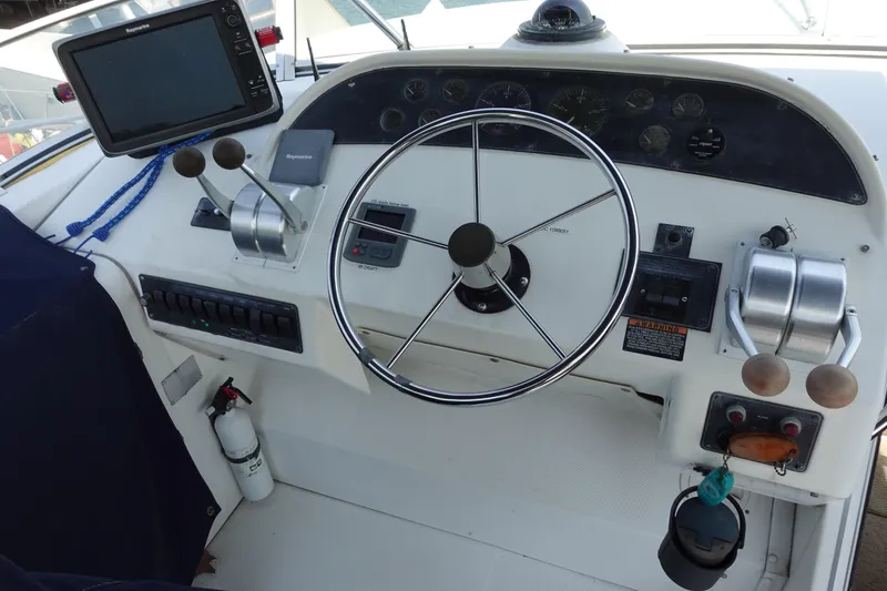 Slide: The Image of 2000 Bayliner 4788 Pilot House Motoryacht helm with steering wheel and navigation controls. - 10