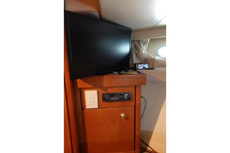 Slide: The Image of Entertainment setup in 2000 Bayliner 4788 Pilot House Motoryacht cabin with TV and clock. - 27