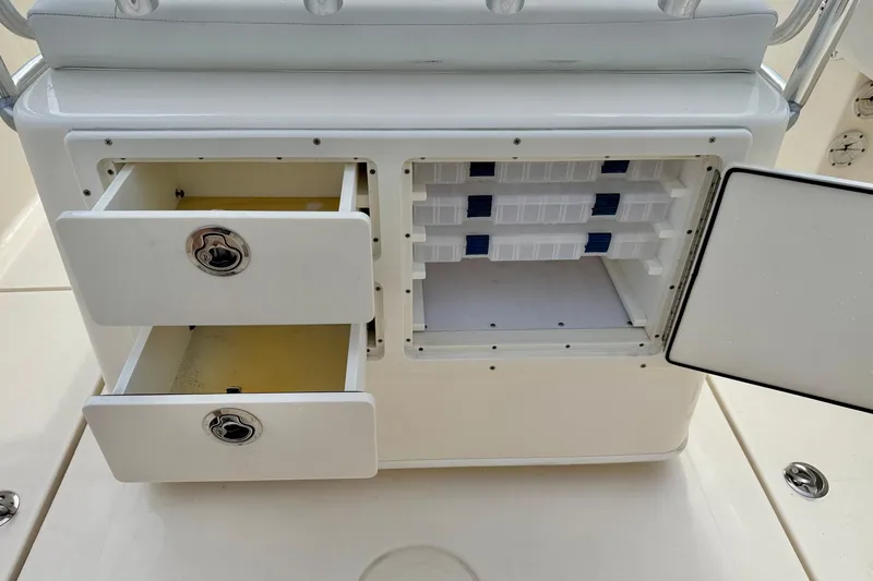 Slide: The Image of 2020 Cobia 237 Center Console storage compartments with open drawers and tackle box slots. - 25