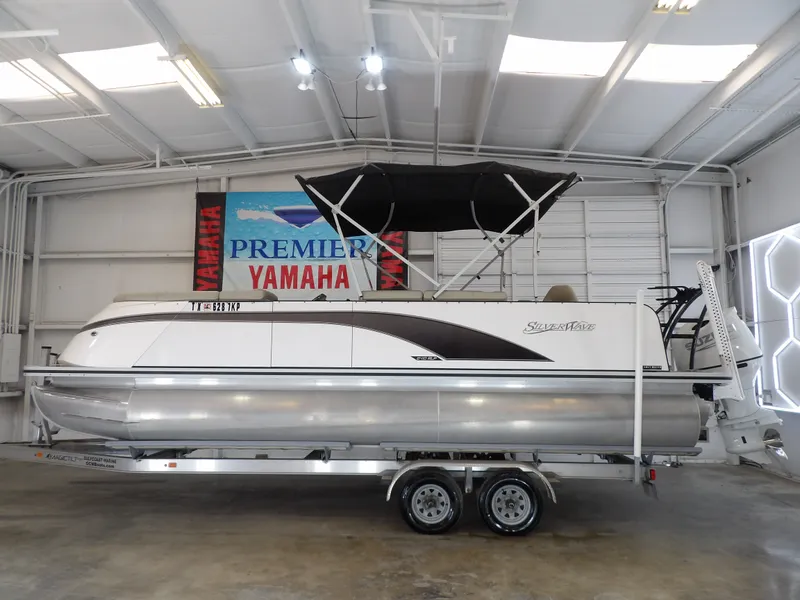 The Image of A 2022 SilverWave 2410 RLP SW3 pontoon boat on a trailer in a showroom. - 1