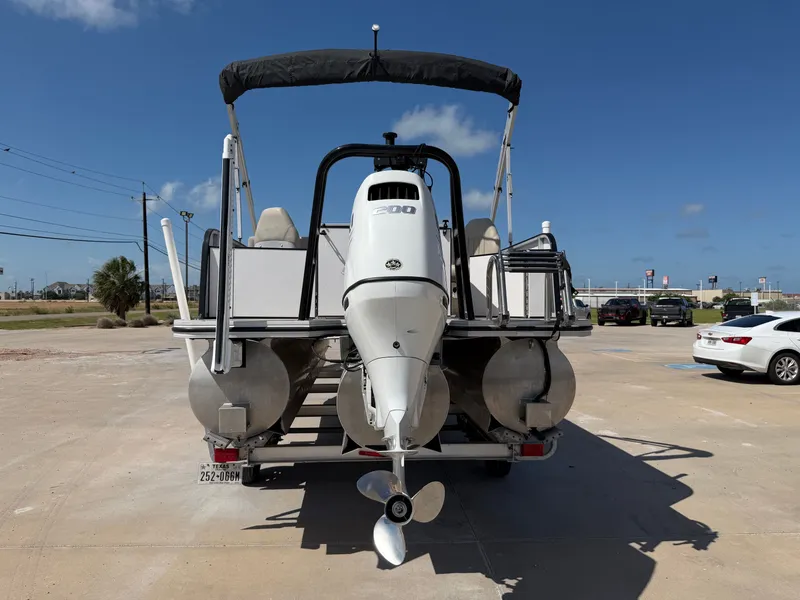 Slide: The Image of A 2022 SilverWave 2410 RLP SW3 pontoon boat with a large outboard motor, parked on a concrete lot. - 26