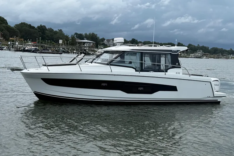 Slide: The Image of 2026 Jeanneau NC 1095 Coupe boat on calm water, overcast sky background. - 59