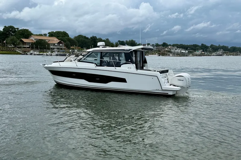 Slide: The Image of 2026 Jeanneau NC 1095 Coupe cruising on a calm river under cloudy skies. - 65