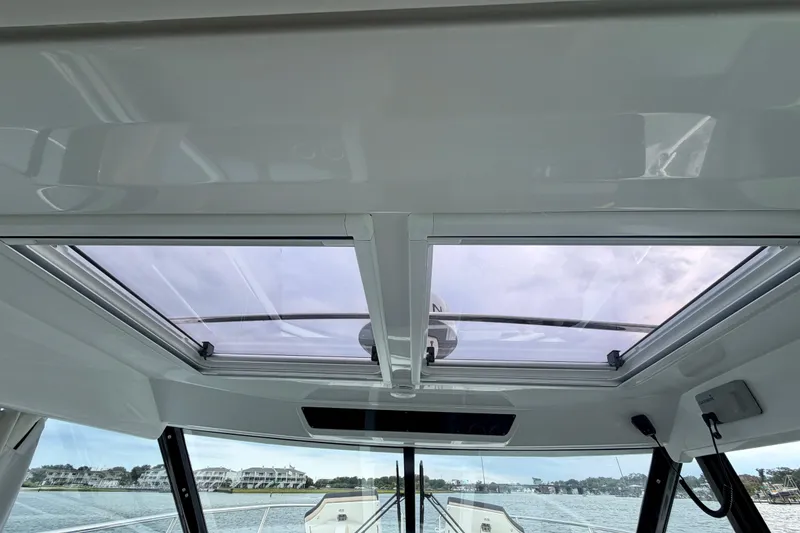 Slide: The Image of 2026 Jeanneau NC 1095 Coupe interior with panoramic sunroof and scenic water view. - 96