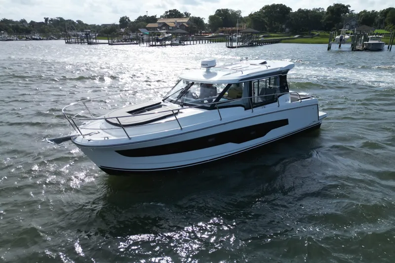 Slide: The Image of 2026 Jeanneau NC 1095 Coupe cruising on a scenic waterway. - 5