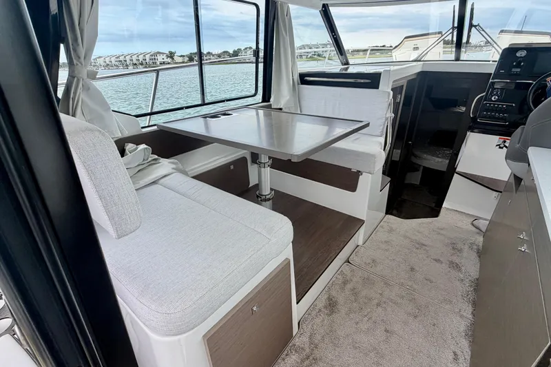Slide: The Image of Interior of 2026 Jeanneau NC 1095 Coupe, featuring a cozy dining area with waterfront views. - 91