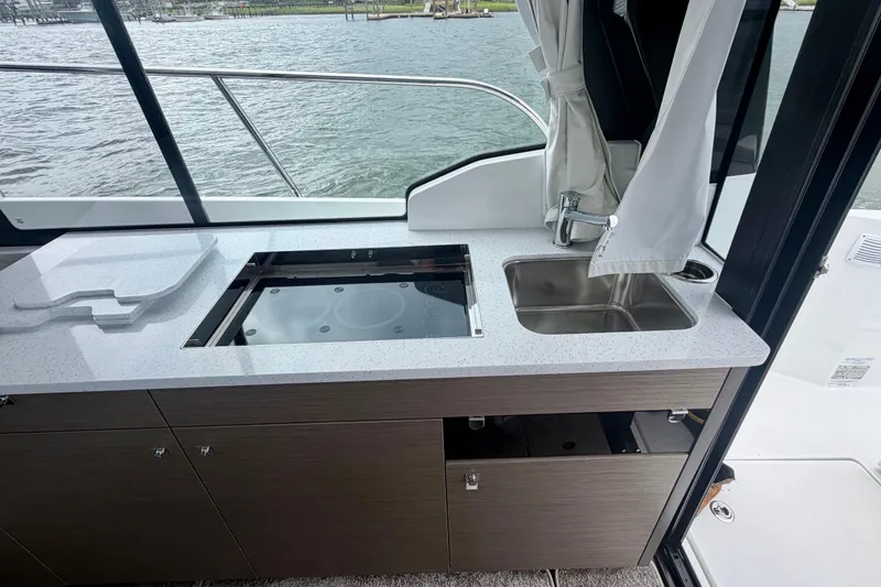 Slide: The Image of Modern kitchenette on 2026 Jeanneau NC 1095 Coupe boat with sink and stove. - 93