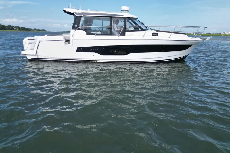 Slide: The Image of 2026 Jeanneau NC 1095 Coupe cruising on calm waters under a clear sky. - 10