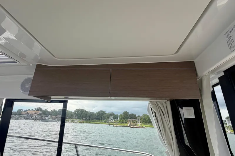 Slide: The Image of Interior view of 2026 Jeanneau NC 1095 Coupe boat with wooden cabinets and water scenery. - 99