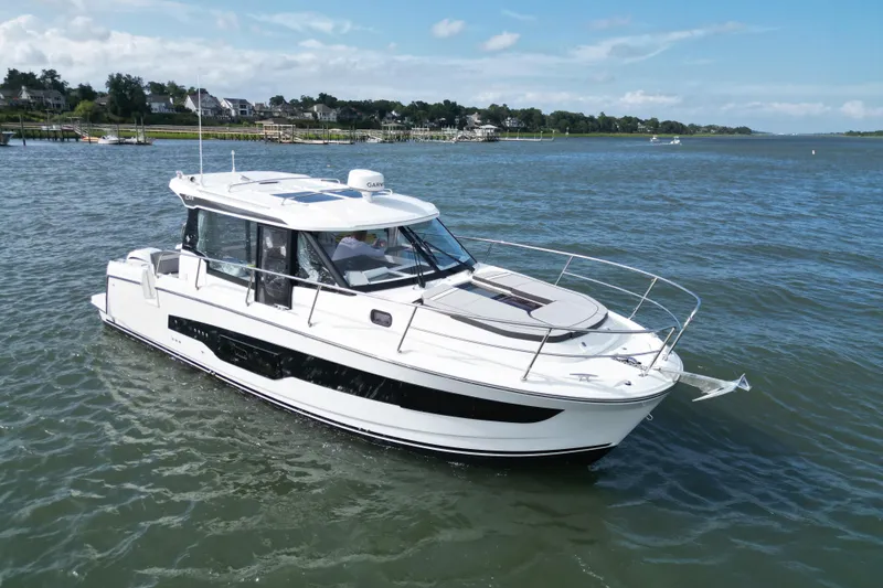 Slide: The Image of 2026 Jeanneau NC 1095 Coupe cruising on a serene lake under a clear blue sky. - 12