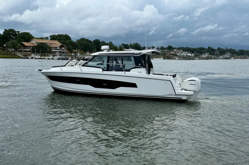 Slide: The Image of 2026 Jeanneau NC 1095 Coupe boat cruising on a calm lake under cloudy skies. - 64