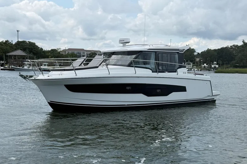 Slide: The Image of 2026 Jeanneau NC 1095 Coupe boat on calm water, cloudy sky background. - 50