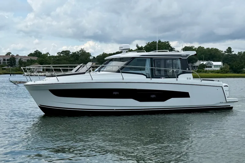 Slide: The Image of 2026 Jeanneau NC 1095 Coupe boat on calm water, cloudy sky background. - 49