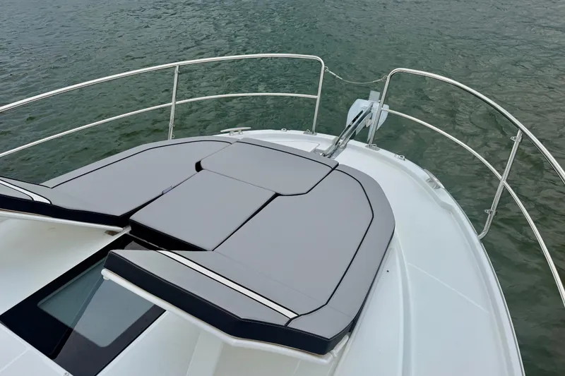 Slide: The Image of 2026 Jeanneau NC 1095 Coupe boat deck with cushioned seating, surrounded by water. - 69