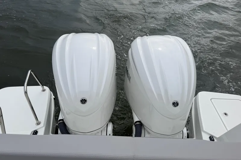 Slide: The Image of Twin outboard engines on a 2026 Jeanneau NC 1095 Coupe boat in water. - 85