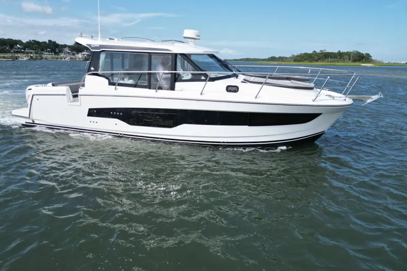 Slide: The Image of 2026 Jeanneau NC 1095 Coupe cruising on calm waters under a clear blue sky. - 9