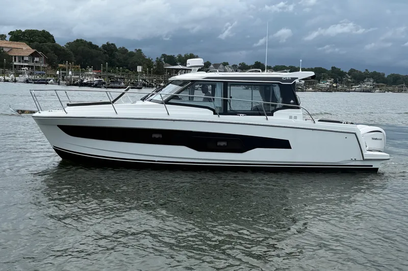Slide: The Image of 2026 Jeanneau NC 1095 Coupe boat on calm water, with scenic shoreline background. - 61