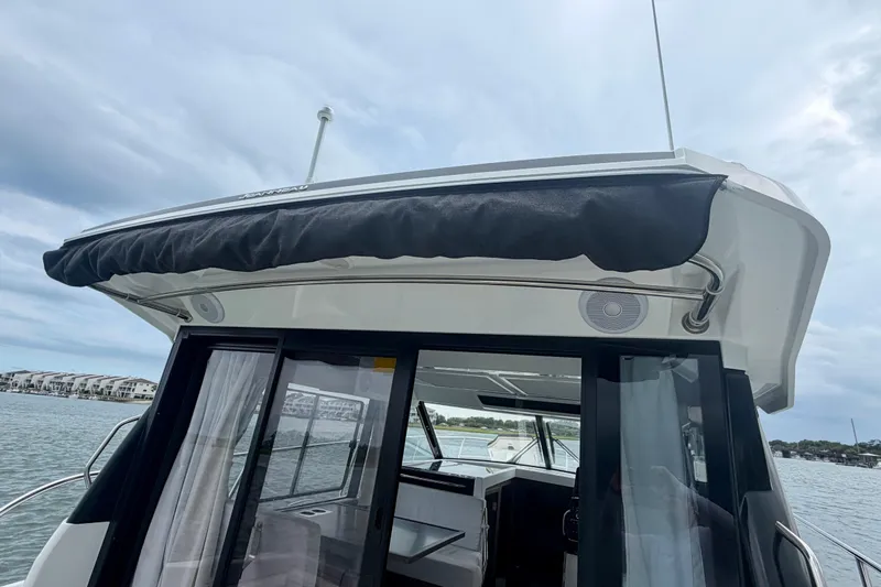 Slide: The Image of 2026 Jeanneau NC 1095 Coupe boat with covered deck, docked by waterfront homes. - 90