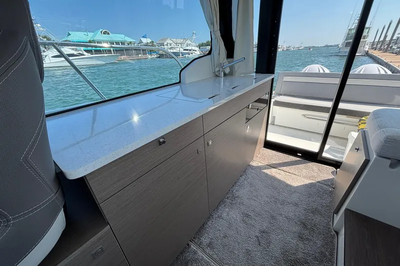 Slide: The Image of Interior view of 2026 Jeanneau NC 1095 Coupe Series 2 yacht with sleek cabinetry and waterfront backdrop. - 12