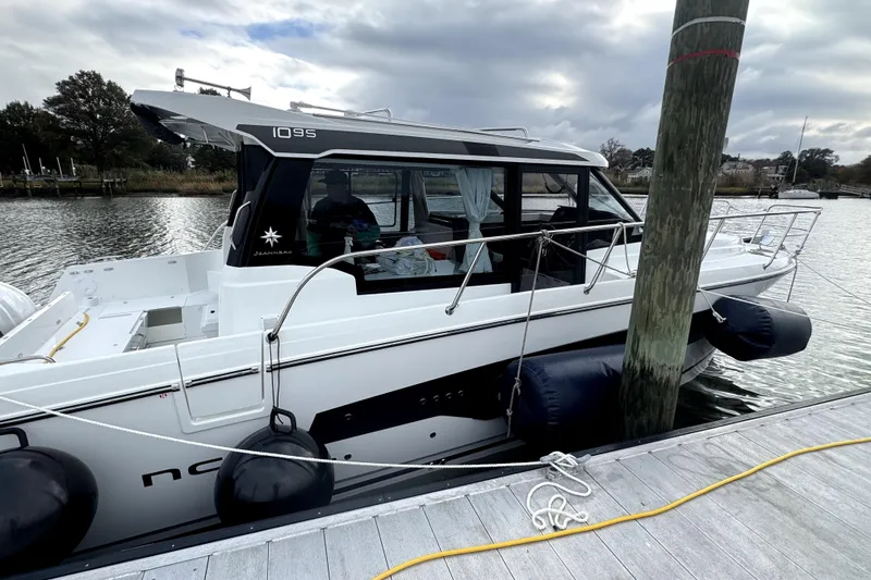 Slide: The Image of 2026 Jeanneau NC 1095 Coupe Series 2 docked at marina, side view. - 2