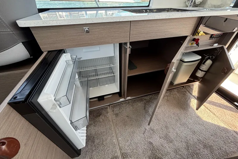 Slide: The Image of Interior view of 2026 Jeanneau NC 1095 Coupe Series 2 kitchen with open fridge and storage. - 30