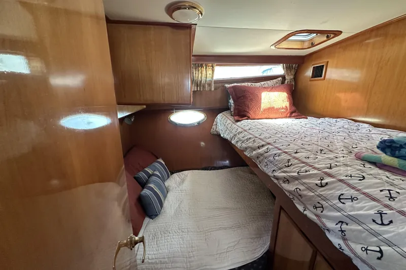 Slide: The Image of Cozy cabin interior of 1998 Mikelson 43 Sportfisher with wooden finish and nautical bedding. - 15