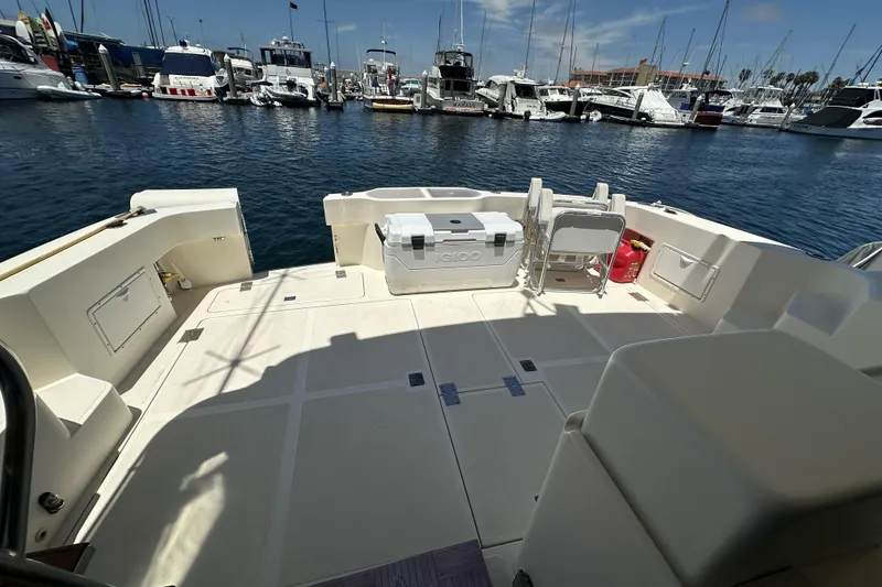 Slide: The Image of 1998 Mikelson 43 Sportfisher yacht deck with cooler, chairs, and marina view. - 10