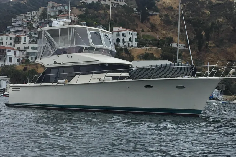 Slide: The Image of 1998 Mikelson 43 Sportfisher yacht anchored near coastal hillside homes. - 1