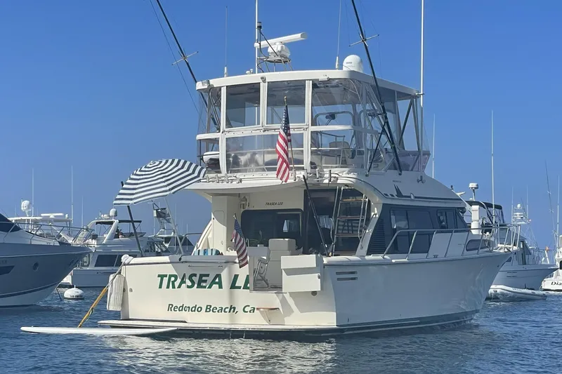 Slide: The Image of 1998 Mikelson 43 Sportfisher yacht docked at Redondo Beach, featuring striped umbrella and American flag. - 4