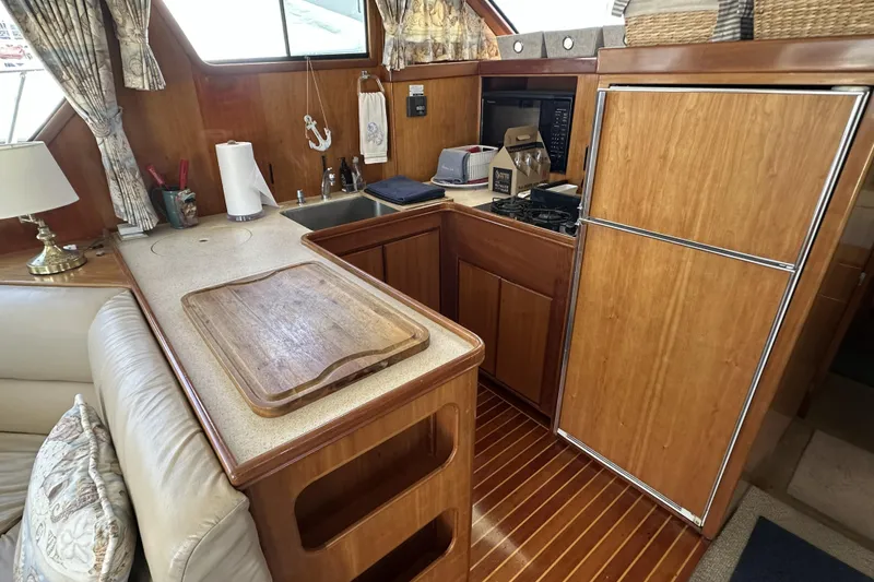 Slide: The Image of Cozy kitchen in 1998 Mikelson 43 Sportfisher yacht with wooden cabinetry and appliances. - 13
