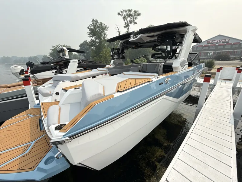 Slide: The Image of A modern 2027 Nautique G23 boat docked. It features a sleek design with blue and white accents. - 6
