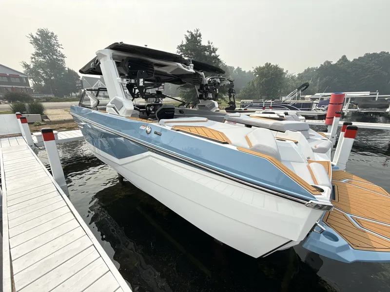 Slide: The Image of A modern 2027 Nautique G23 boat docked. It features a sleek design with blue and white accents. - 5