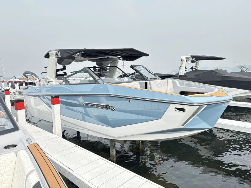 Slide: The Image of A modern 2027 Nautique G23 boat in light blue and white, docked at a pier. - 7