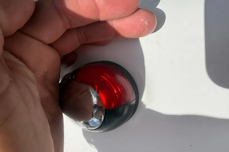 Slide: The Image of Close-up of a hand near a red light on a 2012 Hurricane SunDeck Sport 188 OB boat. - 16