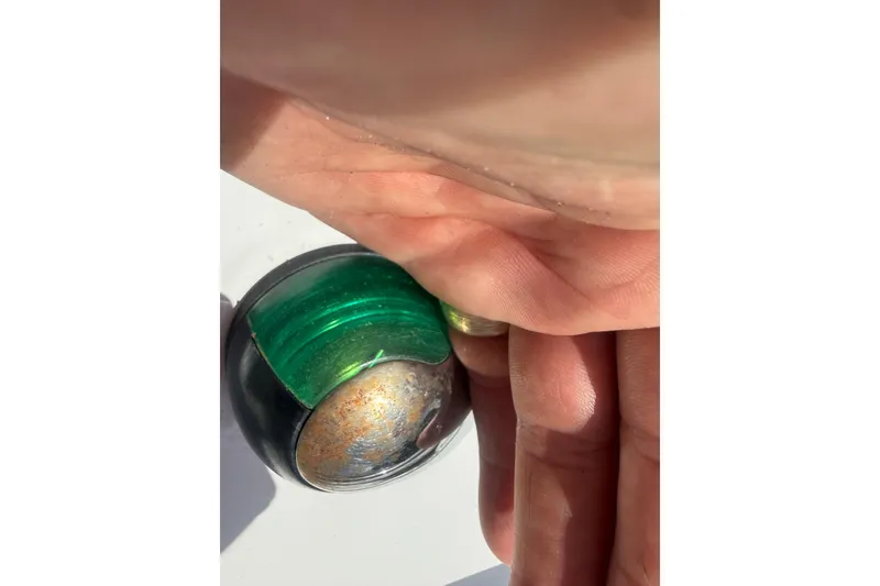 Slide: The Image of Close-up of a hand covering a green navigation light on a 2012 Hurricane SunDeck Sport 188 OB boat. - 17