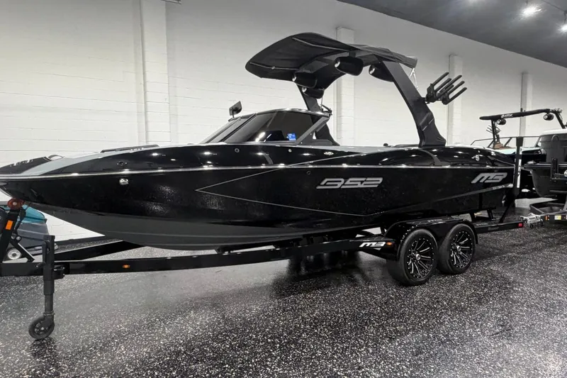 Slide: The Image of 2024 MB B52 23 Classic boat in showroom, sleek black design on trailer. - 2