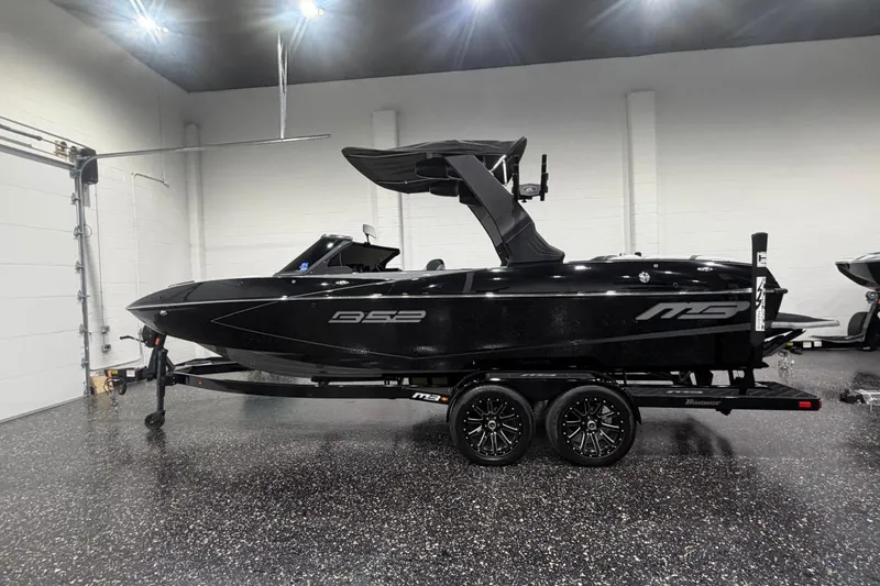 The Image of 2024 MB B52 23 Classic boat in showroom, sleek black design on trailer. - 0