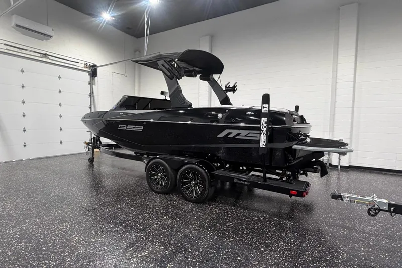 Slide: The Image of 2024 MB B52 23 Classic boat in a showroom, featuring sleek black design and modern trailer. - 1