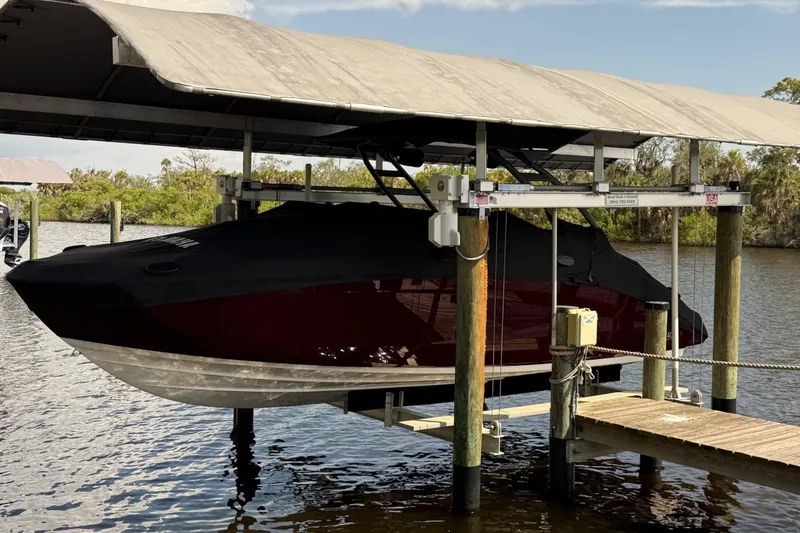 Slide: The Image of 2022 Yamaha Boats 252SD covered and docked on a lift by the water. - 6