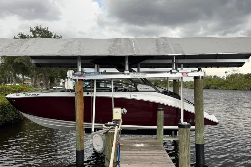 Slide: The Image of 2022 Yamaha Boats 252SD on lift at dock, under cloudy sky. - 3