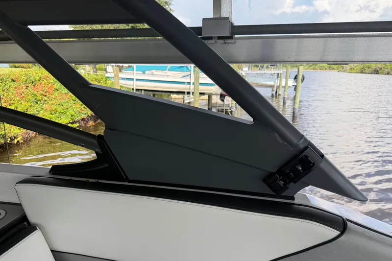 Slide: The Image of 2022 Yamaha Boats 252SD interior detail with open canopy near a dock. - 57