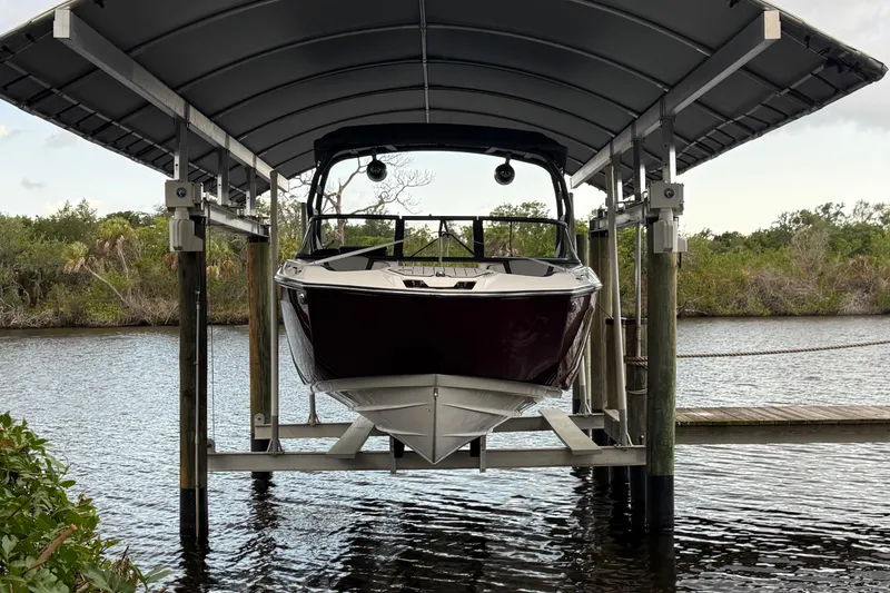 Slide: The Image of 2022 Yamaha Boats 252SD docked under a covered lift on a serene waterway. - 4