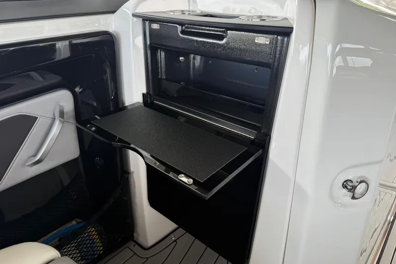 Slide: The Image of 2022 Yamaha Boats 252SD interior storage compartment with open door and sleek design. - 32