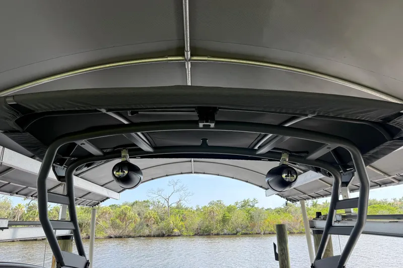 Slide: The Image of 2022 Yamaha Boats 252SD canopy and speakers, docked by a scenic river. - 64