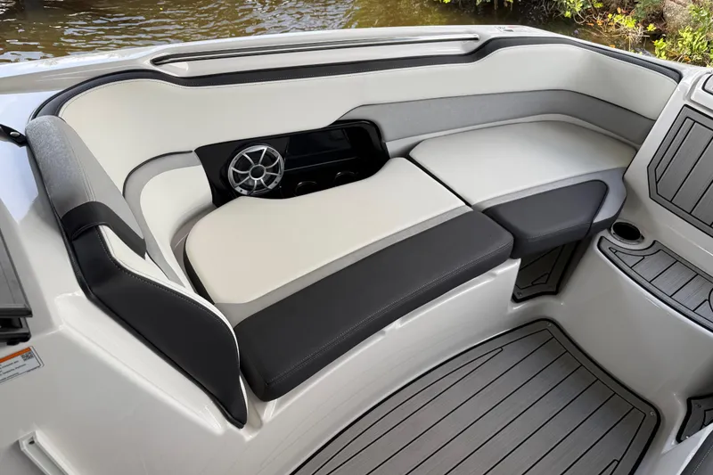 Slide: The Image of 2022 Yamaha Boats 252SD interior with cushioned seating and speaker, dockside view. - 55