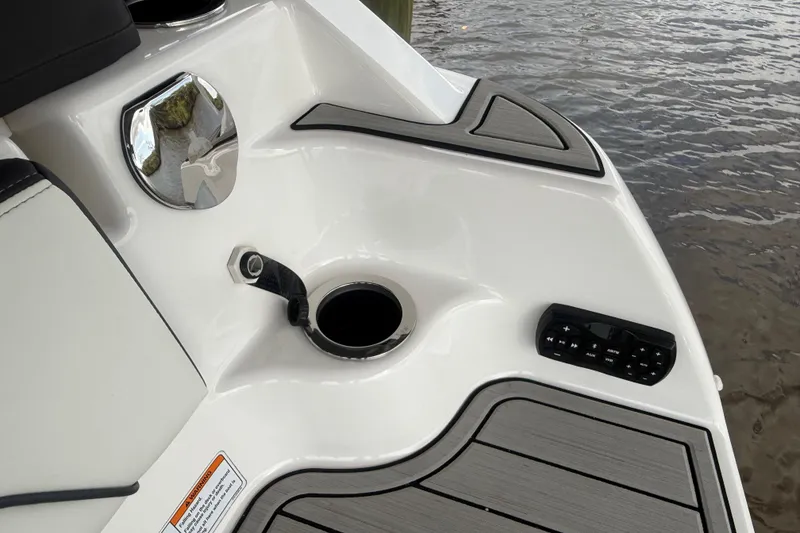 Slide: The Image of 2022 Yamaha Boats 252SD deck with control panel and cup holder by the water. - 11